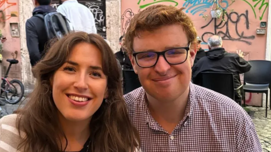 A woman and a man sat together smiling at the camera