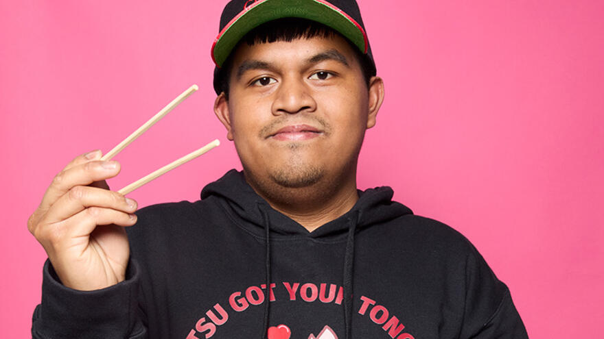 Arjhay in a chopstix sweatshirt and cap holding chopsticks