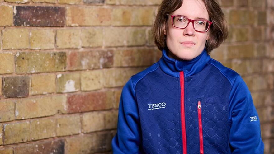 Janis from the Job Squad in a Tesco jacket in front of a brick wall