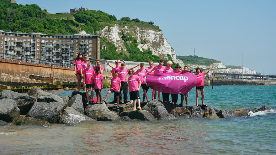 Group of people standing on rocks wearing Mencap t-shirts