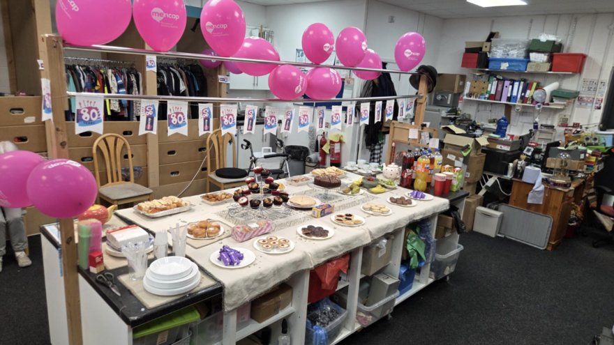 The inside of a Mencap shop decorated with pink Mencap 80 balloons