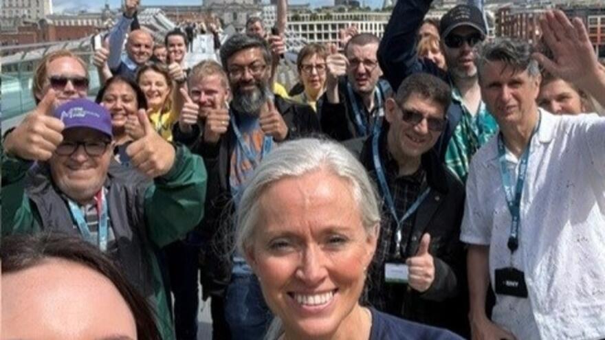 A crowd of supporters with their thumbs up standing outside in London