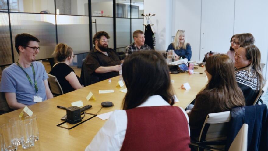 Lots of people sitting around a meeting table in an office