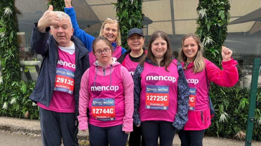 A group of people in Mencap running vests with their thumbs up