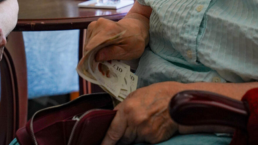A person sitting in a chair counting money in a purse