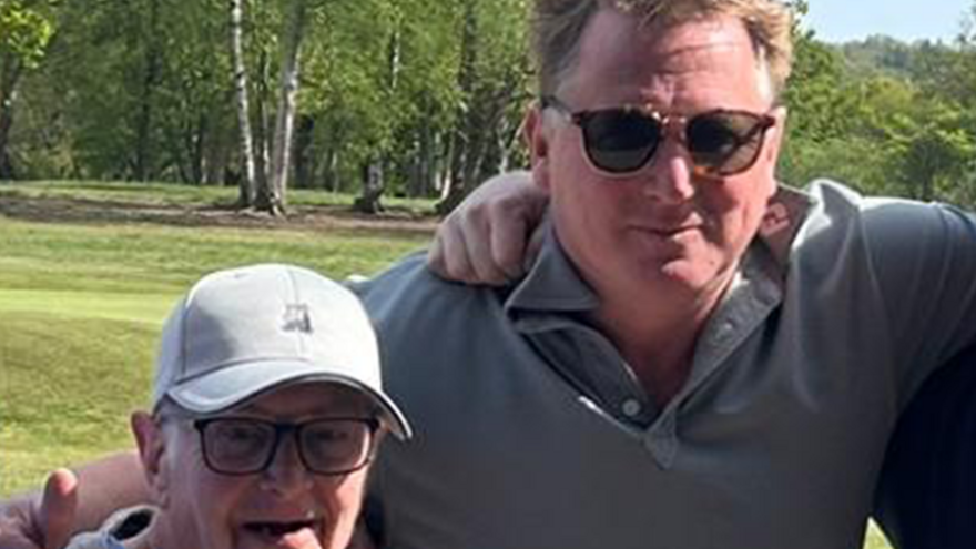 Two men with their arms around each others shoulders on a golf course