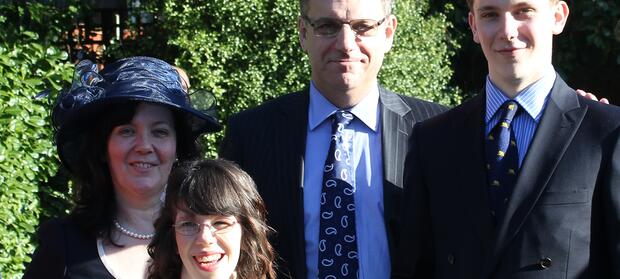 Mother and father stood with daughter and son outside smiling for camera.