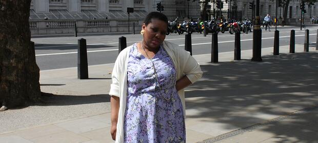 Woman stood outside with hand on hip, looking into camera.