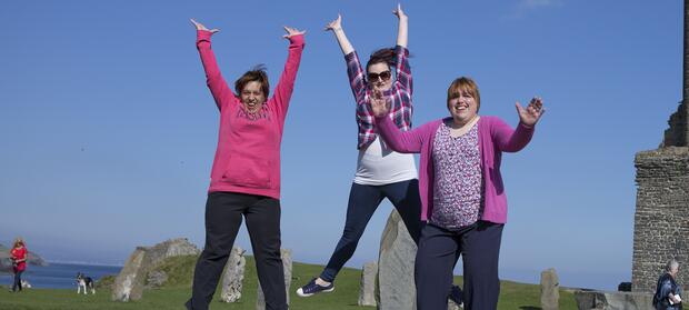 Three people outside jumping in the air