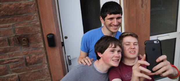 Friends, and Golden Lane Housing tenants, Lewis, Tom and Ryan stood together posing for selfie in front of house.
