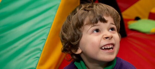 Young boy with brown curly hair smiling and looking up.