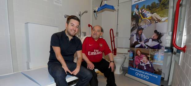 Alex Brooker and Leroy Binns sit inside Arsenal's new Changing Places toilet to celebrate its opening.