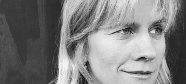 Black and white photograph of woman's face. She has light hair and a fringe.