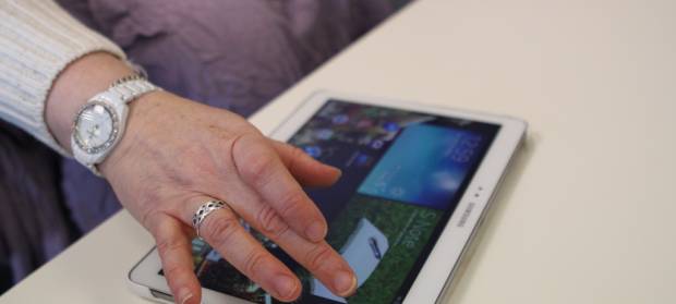 Hand wearing rings hovered above an iPad which is resting on a table.