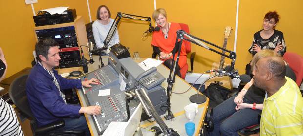Group of people sat round table in a radio studio