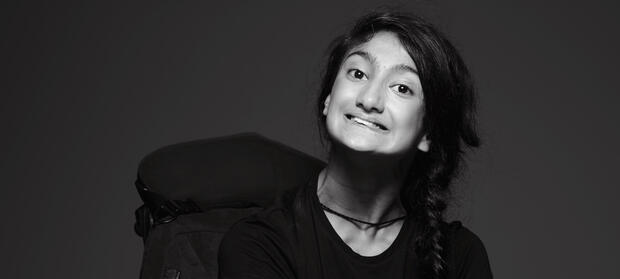 Woman with long dark hair in a plait sat in wheelchair, smiling at camera