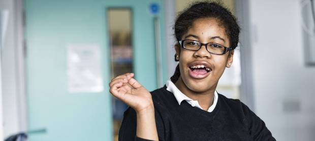 Female school pupil sat in classroom with her hand raised