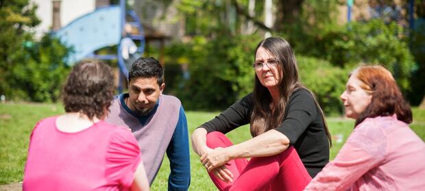 Group of people sat together in park chatting