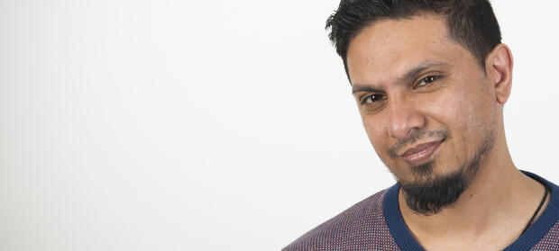 Man with dark hair and goatee beard smiling at camera.