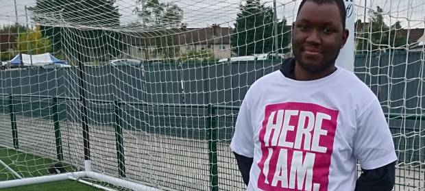 Man wearing a Here I am t-shirt stood in front of football goal