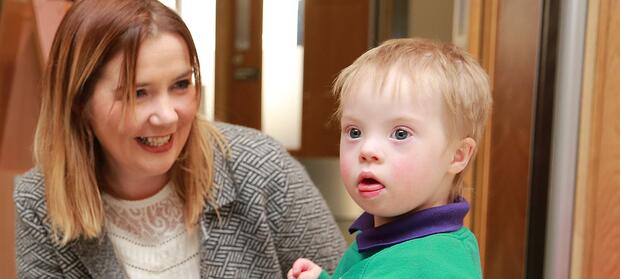 Young boy looking into distance, woman next to him is smiling