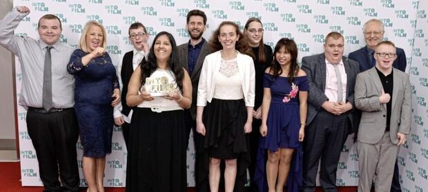 Group of people stood on red carpet at awards ceremony.