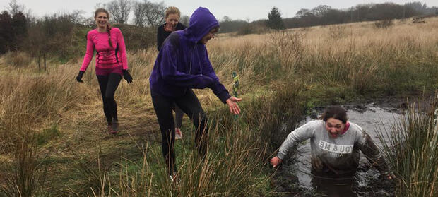 Woman in field wading through waist-high mud