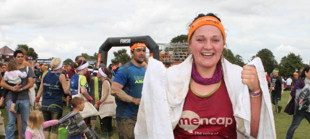 Woman with Mencap vest on and towel round her shoulders at finish of race.