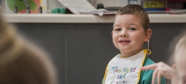 Young boy in nursery sat looking into camera.