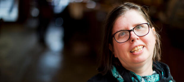 Woman with dark hair and glasses smiles into camera