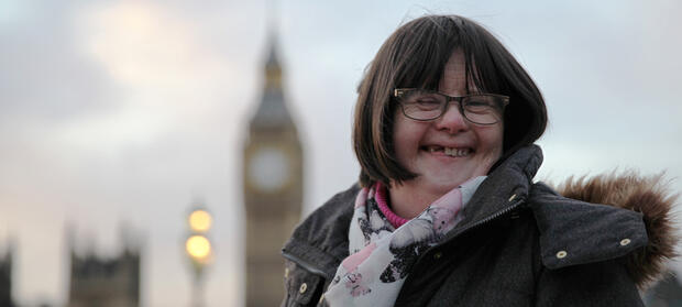 Woman with dark hair, smiling at the camera, with Big Ben in the background