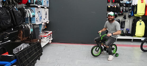 Man in shop riding a small bicycle
