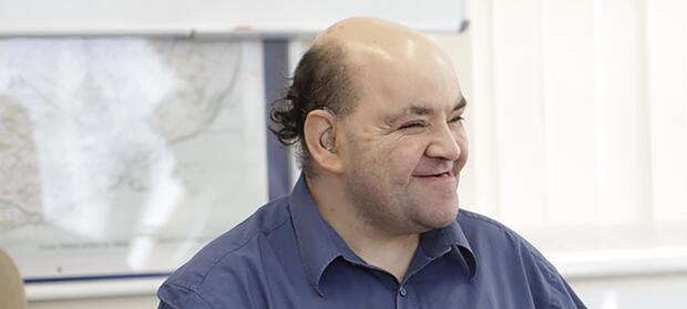 Main wearing dark blue shirt smiling looking off to the side