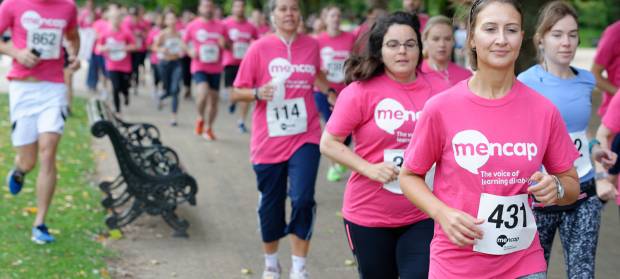 Runners in park all wearing pink Mencap t-shirts
