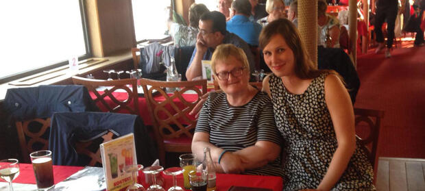 Two women sat next to each other at a table in a restaurant.