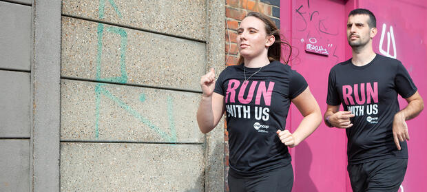 Two female runners running outside wearing Mencap Run With Us t-shirts.