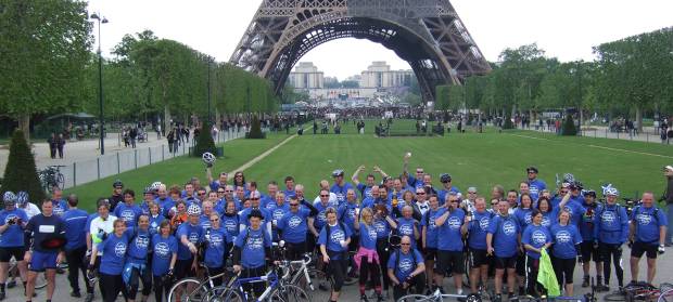 Large group of cyclists gathered in front of the Eiffel Tower.