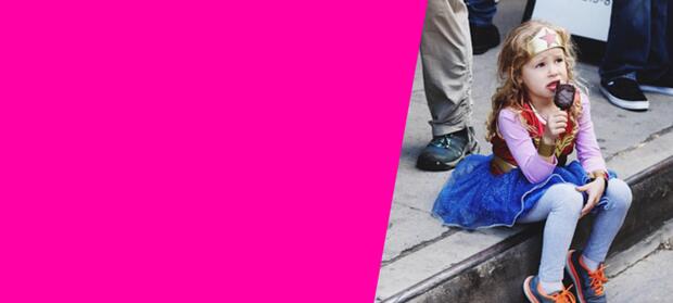 girl eating an ice cream sitting on the kerb with a superhero costume on