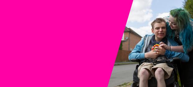 Man with a learning disability in a wheelchair pushed by a woman carer who is talking to him