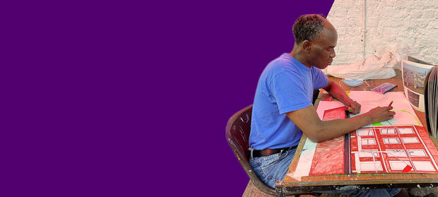 A man sits at a desk creating artwork