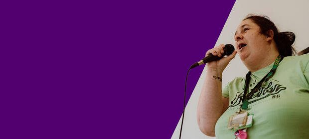 A woman in a green t-shirt speaks into a microphone