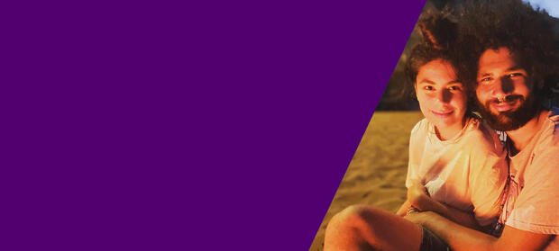 A man and woman sit on the beach and smile.