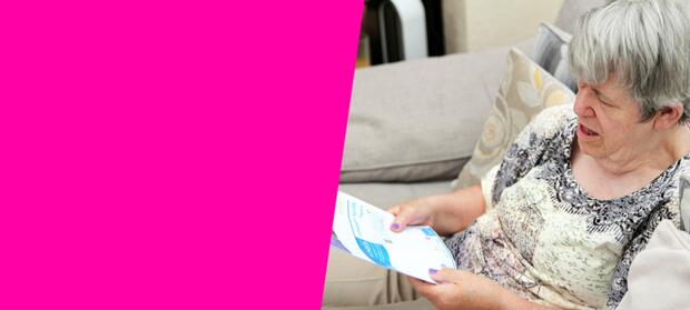 A woman sitting on a sofa reading her electricity bill