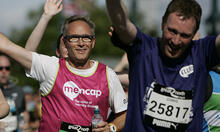 Runners running together in race, one male running with his arm outstretched, waving
