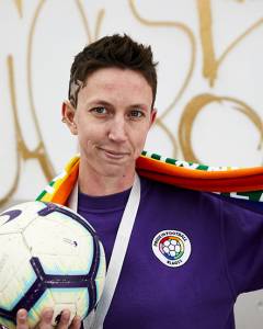 Picture of a woman; Sas in a football shirt and holding a football