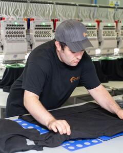 A man smoothing out an item of clothing on a table. 