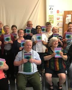 Members of Tameside Me Time proudly old up a book of poems they have contributed to.