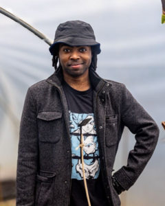 A man standing in a garden wearing a hat
