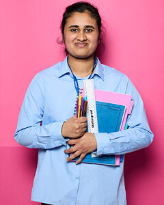 Diviyha holding some school books, pens and a ruler
