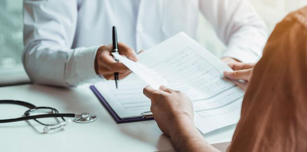 A doctor handing over a form to a patient at a desk